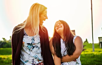 Portrait of trisomie 21 adult girl smiling outside at sunset with a support person