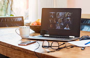 Laptop sitting on a desk with a virtual meeting in progress.