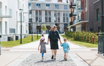 Mother and two her kids - a boy and a girl, holding hands walking along the town