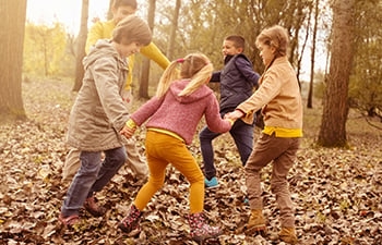 Children holding hands in a circle playing outside in the Autumn.