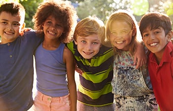 A group of youth standing together with their arms over eachother's shoulders.