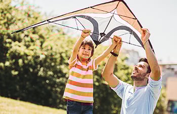 An adult helping a youth to fly a kite.